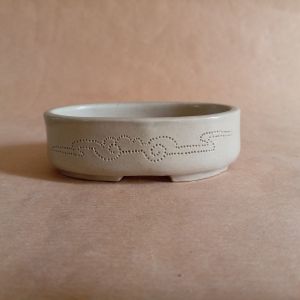 Piccolo vasso ovale in gres smaltato, con nuvole stilizzate incise sulla superficie.