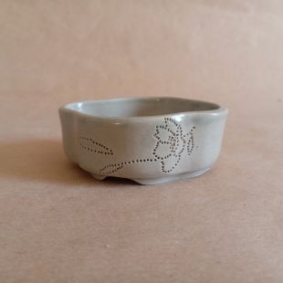 Piccolo vaso per mame bonsai in gres smaltato con un rametto di ciliegio inciso a piccoli puntini. Da un lato il ramo ha un fiore appena sbocciato, dall'altro due foglioline.