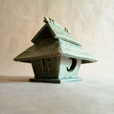 Brucia incensi a forma di capanna tradizionale giapponese. Di un verde tenero come un germoglio in primavera. Sul tetto corre una pianta di zucca.